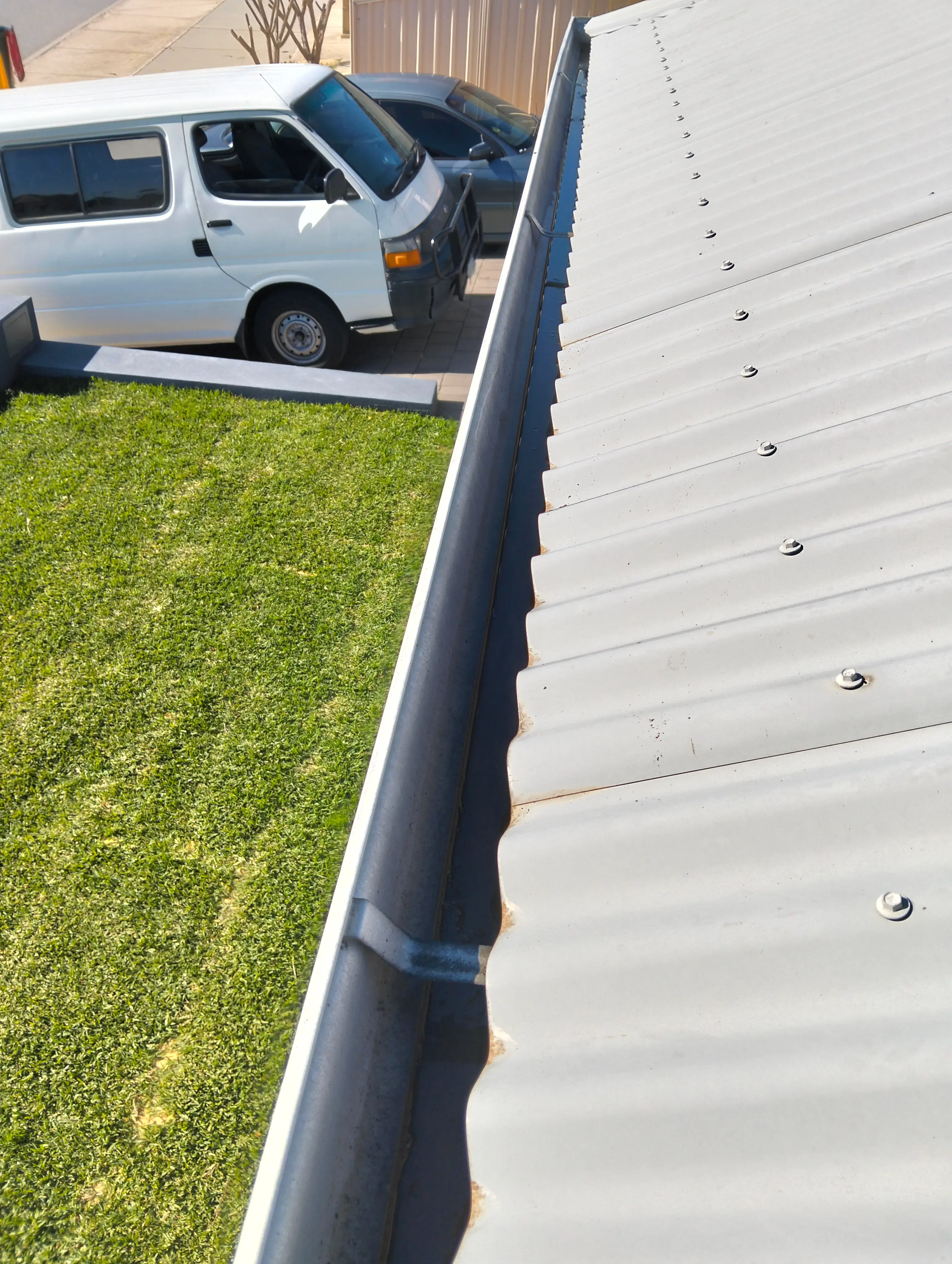 Clear roof gutter running beside a corrugated metal roof